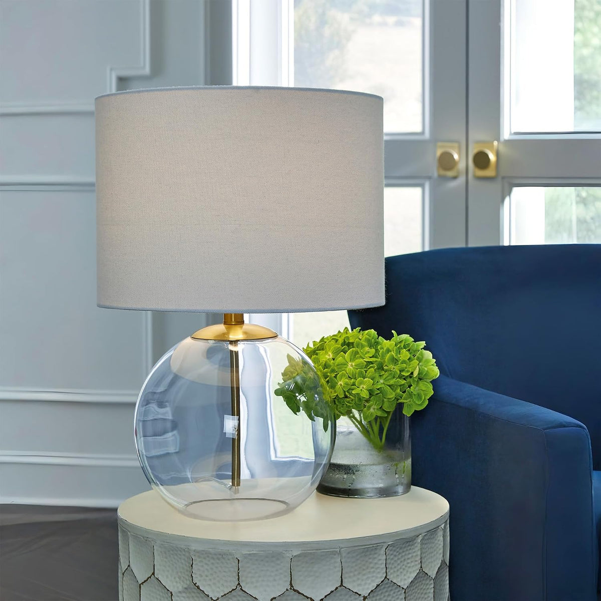 Signature Design by Ashley Glass Table Lamp, Modern Bedside, Clear & Brass | White fabric drum shade, Compact round clear glass profile for modern nightstands, Samder Series