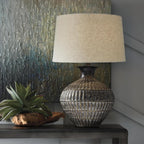Signature Design by Ashley Magan Metal Table Lamp, 28", Antique Bronze | Antique bronze-tone metal base, Textured pattern, Fabric modified drum shade, Living room or entryway use, 3-way switch