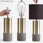 Signature Design by Ashley Jacek Contemporary Table Lamp Set of 2 | Textured faux concrete and brass-finished metal, Black drum shade with goldtone foil interior, Living room and bedside use