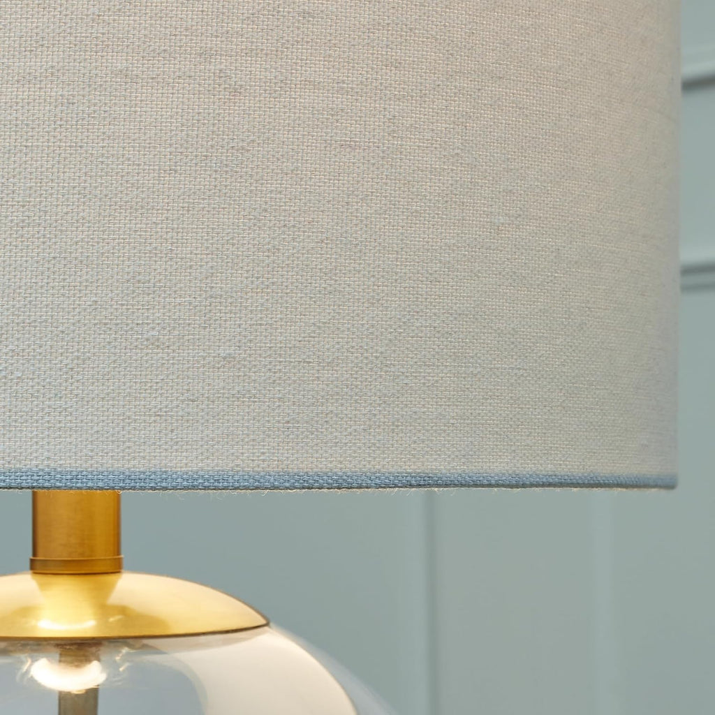 Signature Design by Ashley Glass Table Lamp, Modern Bedside, Clear & Brass | White fabric drum shade, Compact round clear glass profile for modern nightstands, Samder Series